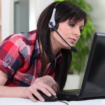 woman with headset on laptop voip dark hair